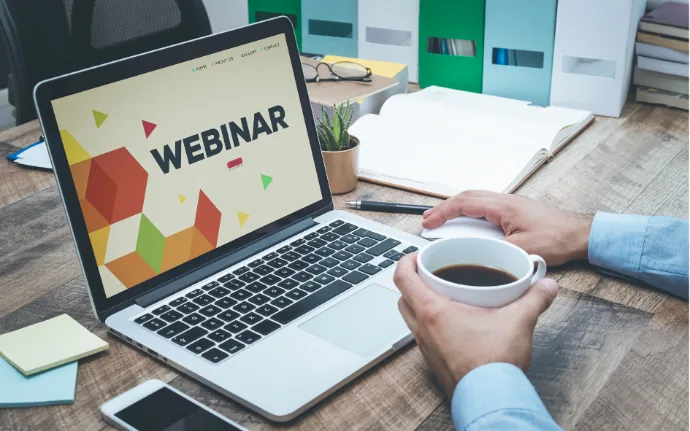 Laptop bertuliskan webinar di meja kerja